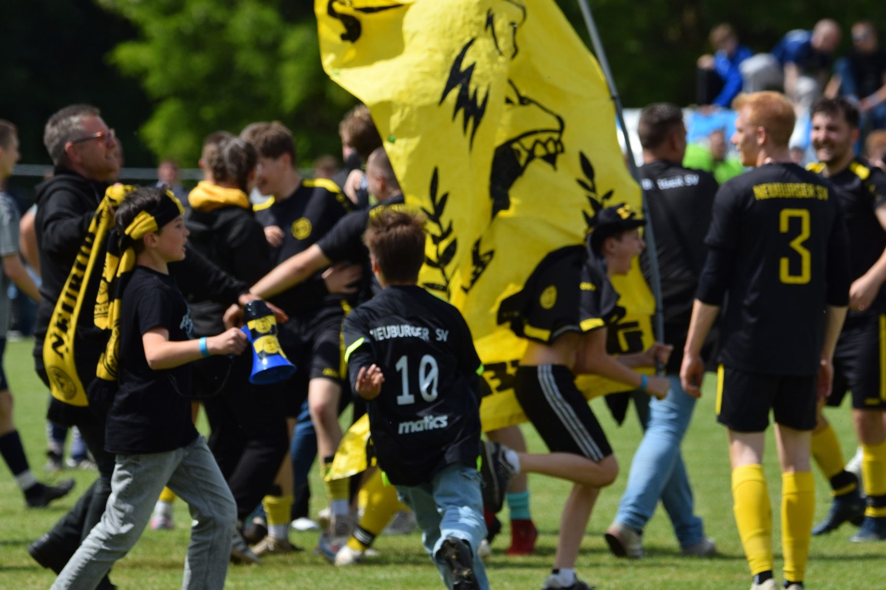Fans und Mannschaft des Neuburger SV feiern den Kreispokalsieg mit großer gelber Fahne